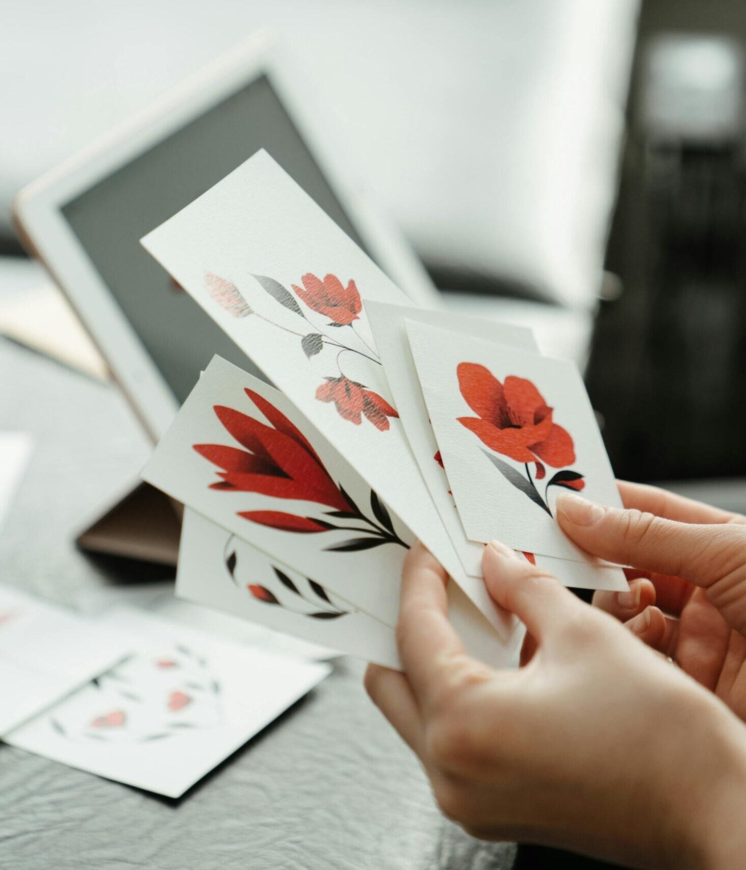 Close-up of hands holding red flower sketches in a tattoo studio.